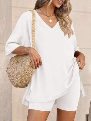 White V-neck two-piece set with loose tee and biker shorts, styled with a straw bag.