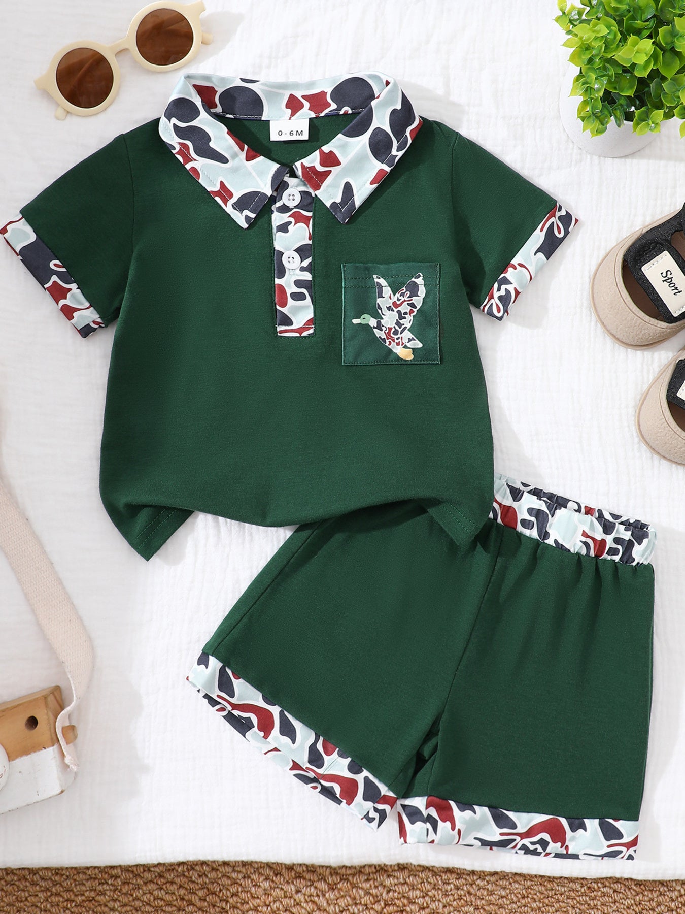 Dark green baby polo shirt and shorts set with camouflage trim and duck pocket detail.
