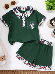 Dark green baby polo shirt and shorts set with camouflage trim and duck pocket detail.