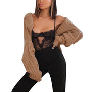 Camel ribbed knit shrug with extended sleeves, worn open over a black lace bodysuit.
