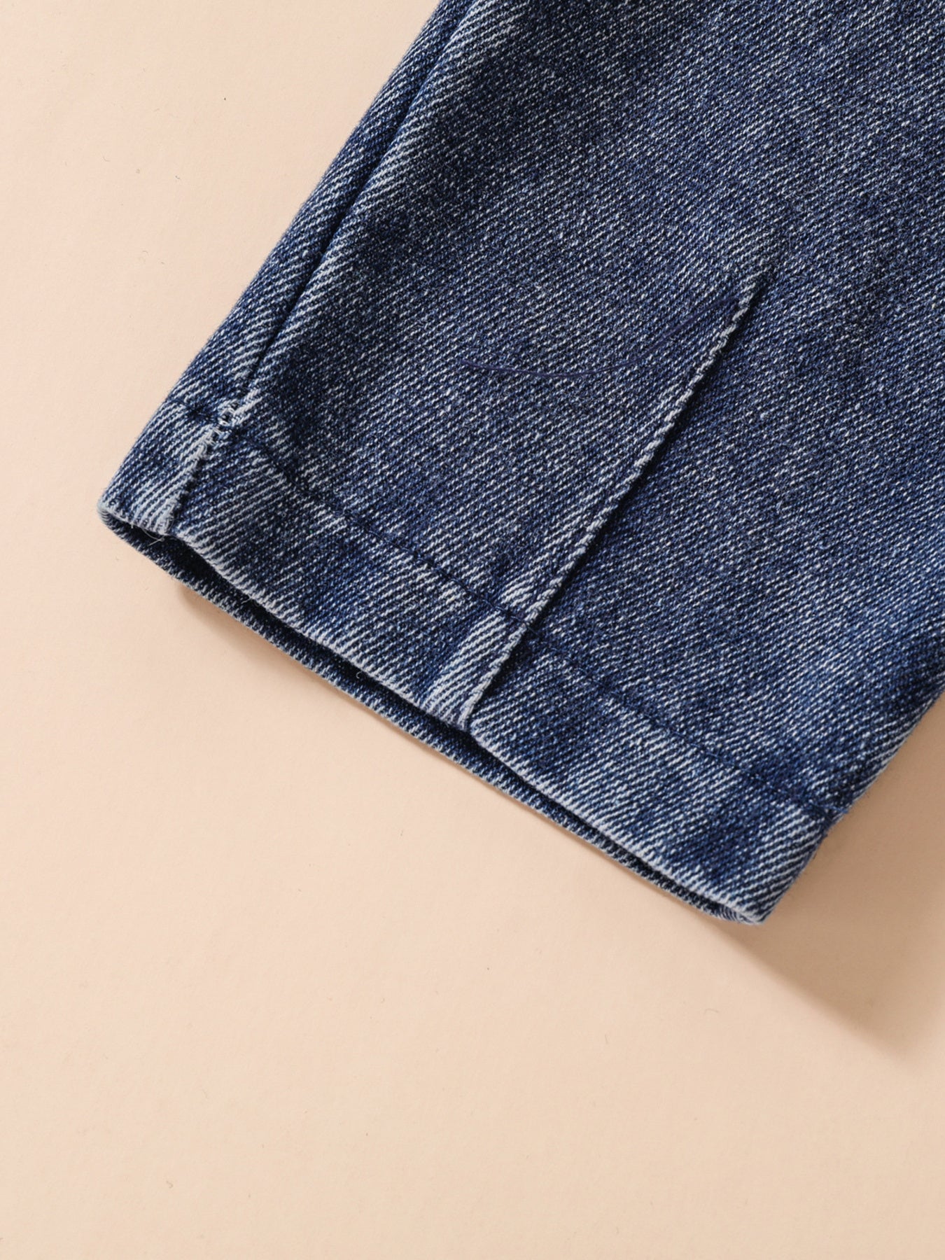 Acid-wash denim jeans detail, showing stitching and hem.