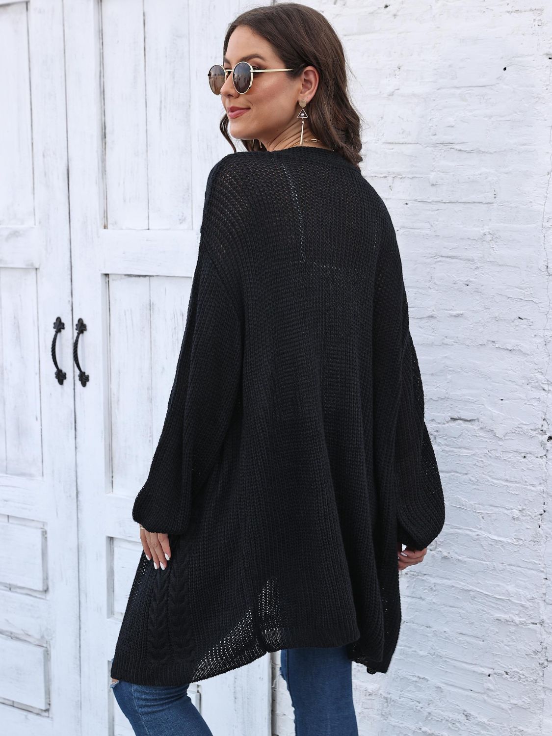 Black cable knit cocoon cardigan with balloon sleeves and open knit hem.