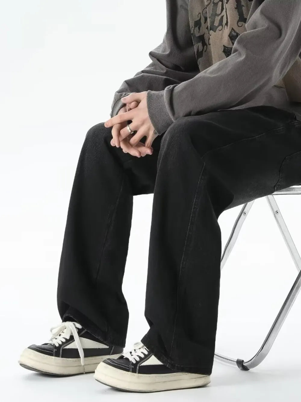 Men's relaxed fit black jeans with drawstring waist, styled with sneakers.