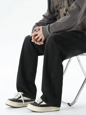 Men's relaxed fit black jeans with drawstring waist, styled with sneakers.