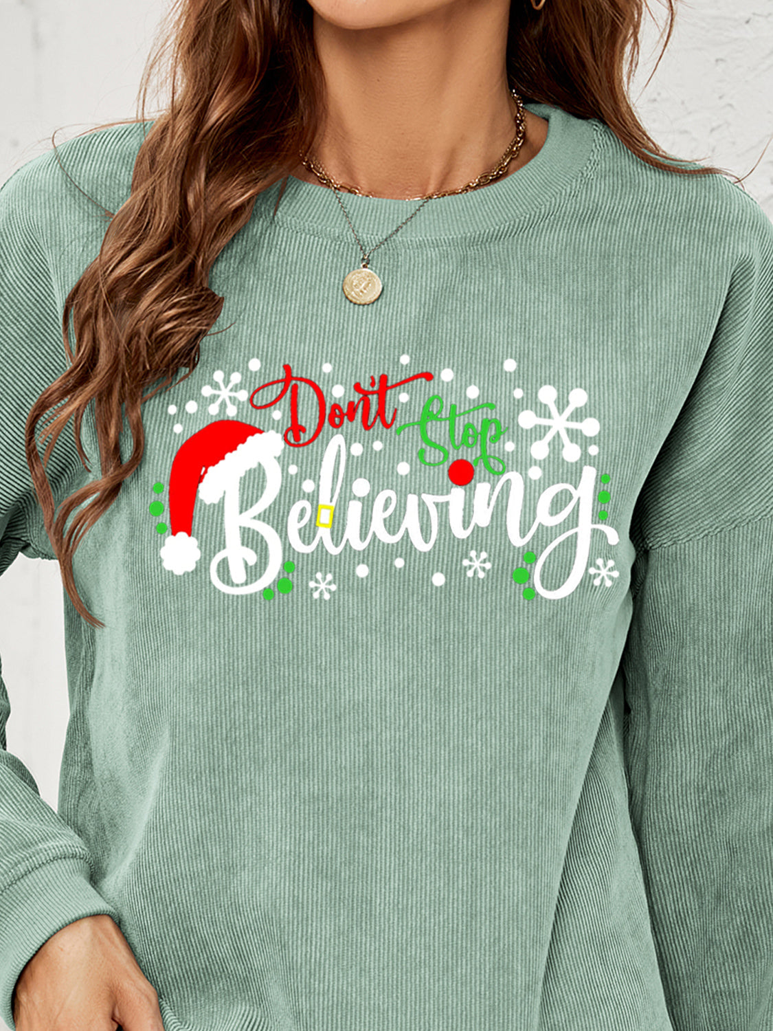 Sage corduroy crewneck sweatshirt with Christmas graphic and Santa hat detail.