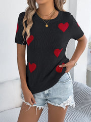 Black knit t-shirt with scattered red heart motifs and short sleeves.