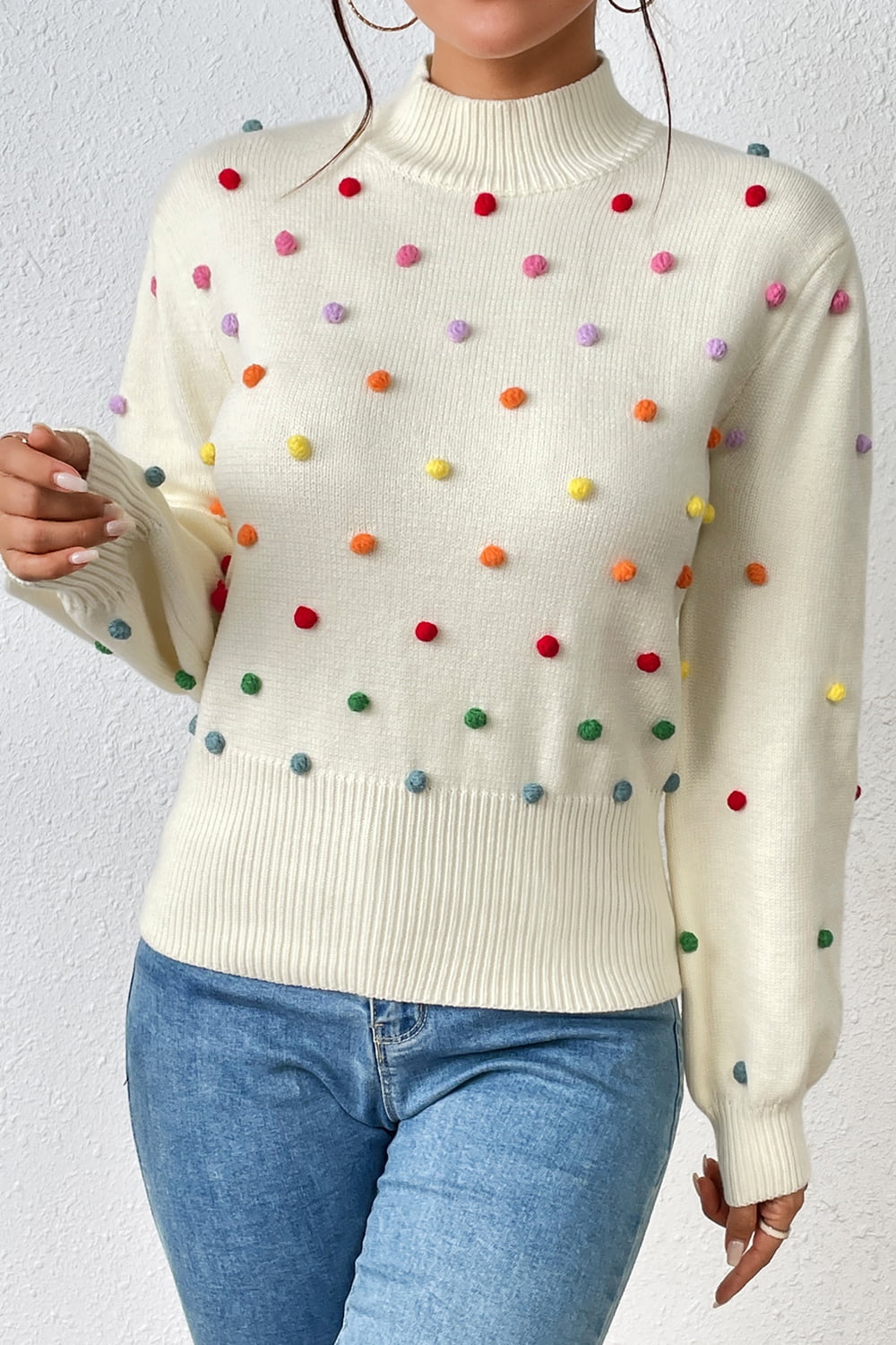 Cream knit sweater with colorful pom-pom embellishments and mock neck