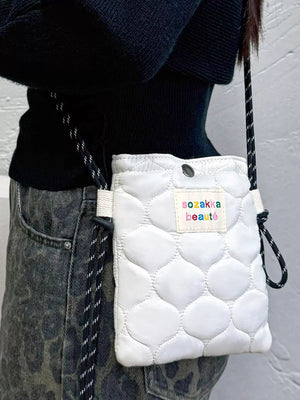 Vibrant quilted mini crossbody bag in ivory with a colorful logo patch and adjustable strap.