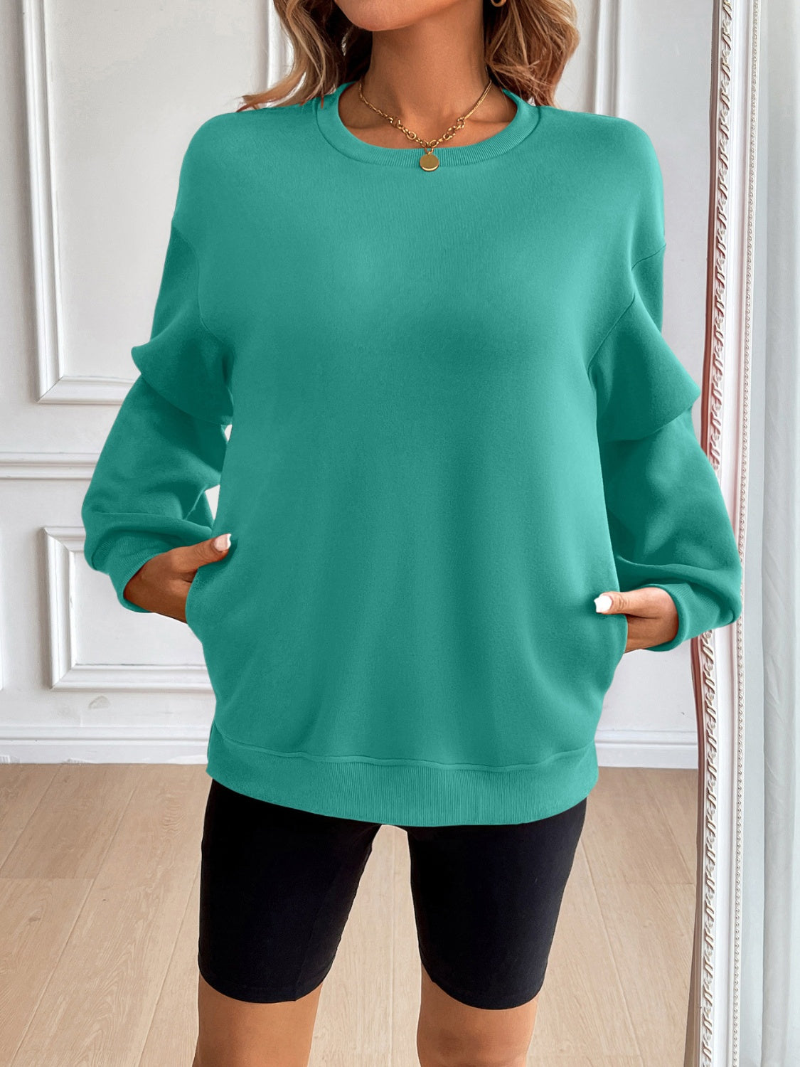 Teal relaxed fit sweatshirt with crewneck, long sleeves, and front pockets.