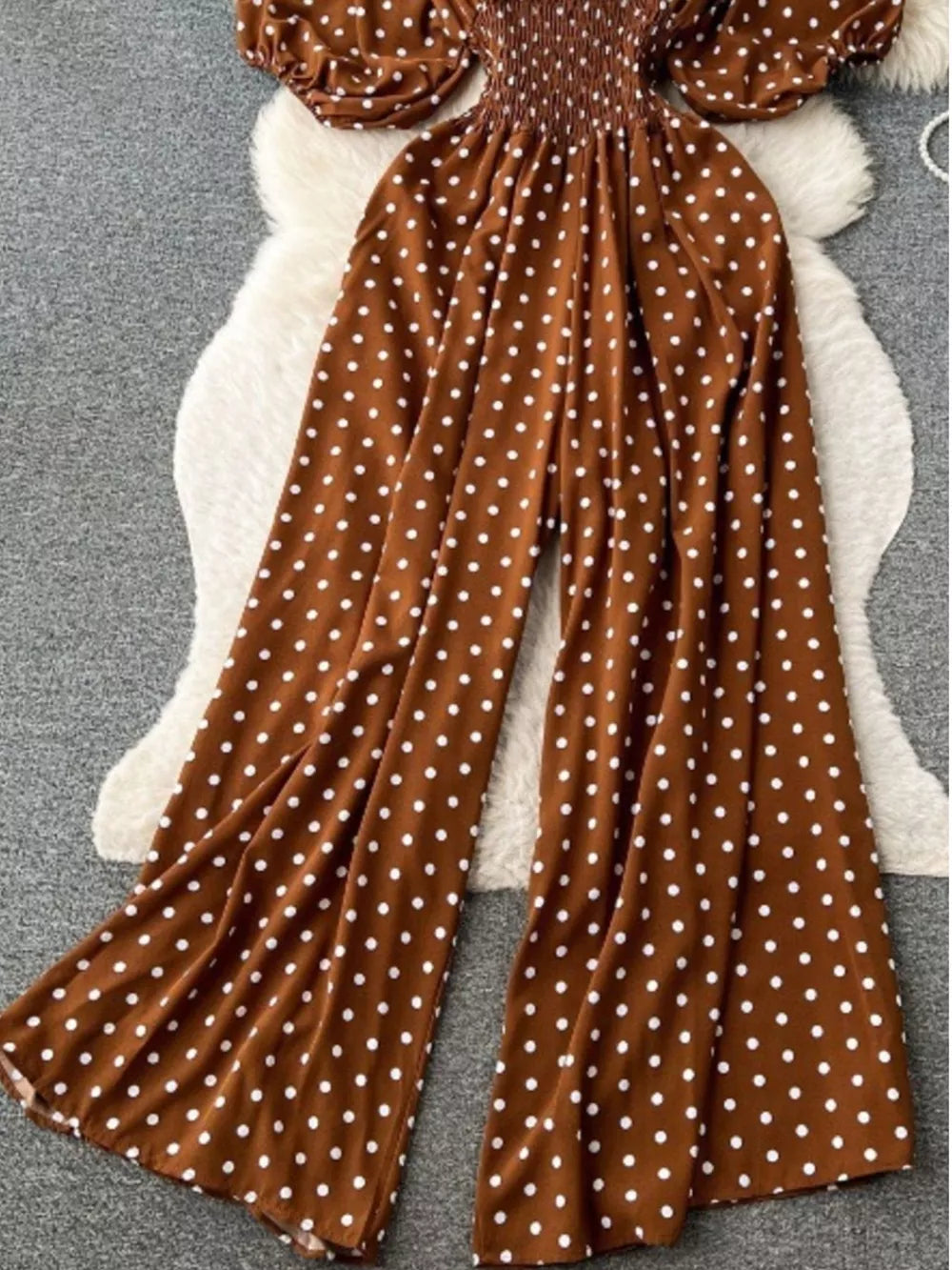 Caramel polka dot smocked wide-leg romper with puff sleeves.