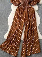 Caramel polka dot smocked wide-leg romper with puff sleeves.