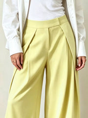 Yellow wide-leg pants with pleats and a high waist, styled with a white shirt.
