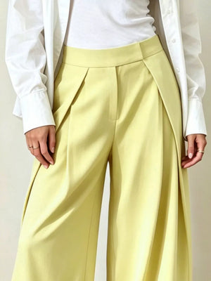 Yellow wide-leg pants with pleats and a high waist, styled with a white shirt.
