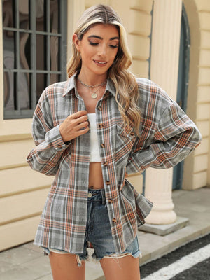 Plaid collared long sleeve shirt in gray with orange and white plaid, featuring button-down front and chest pockets.