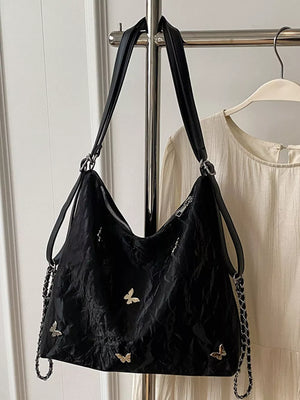 Black shoulder bag with crinkled texture and butterfly embellishments.