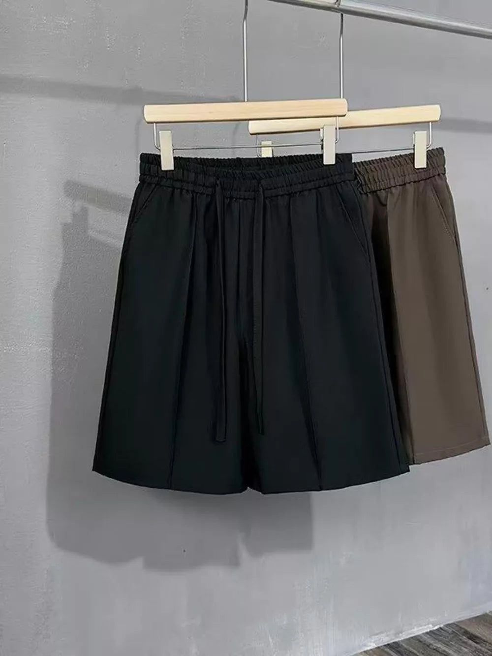 Black and brown men's chino shorts with drawstring waist and pleats.