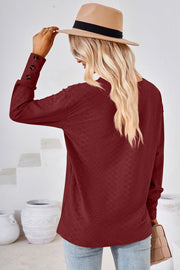 Burgundy textured V-neck blouse with button cuff long sleeves.