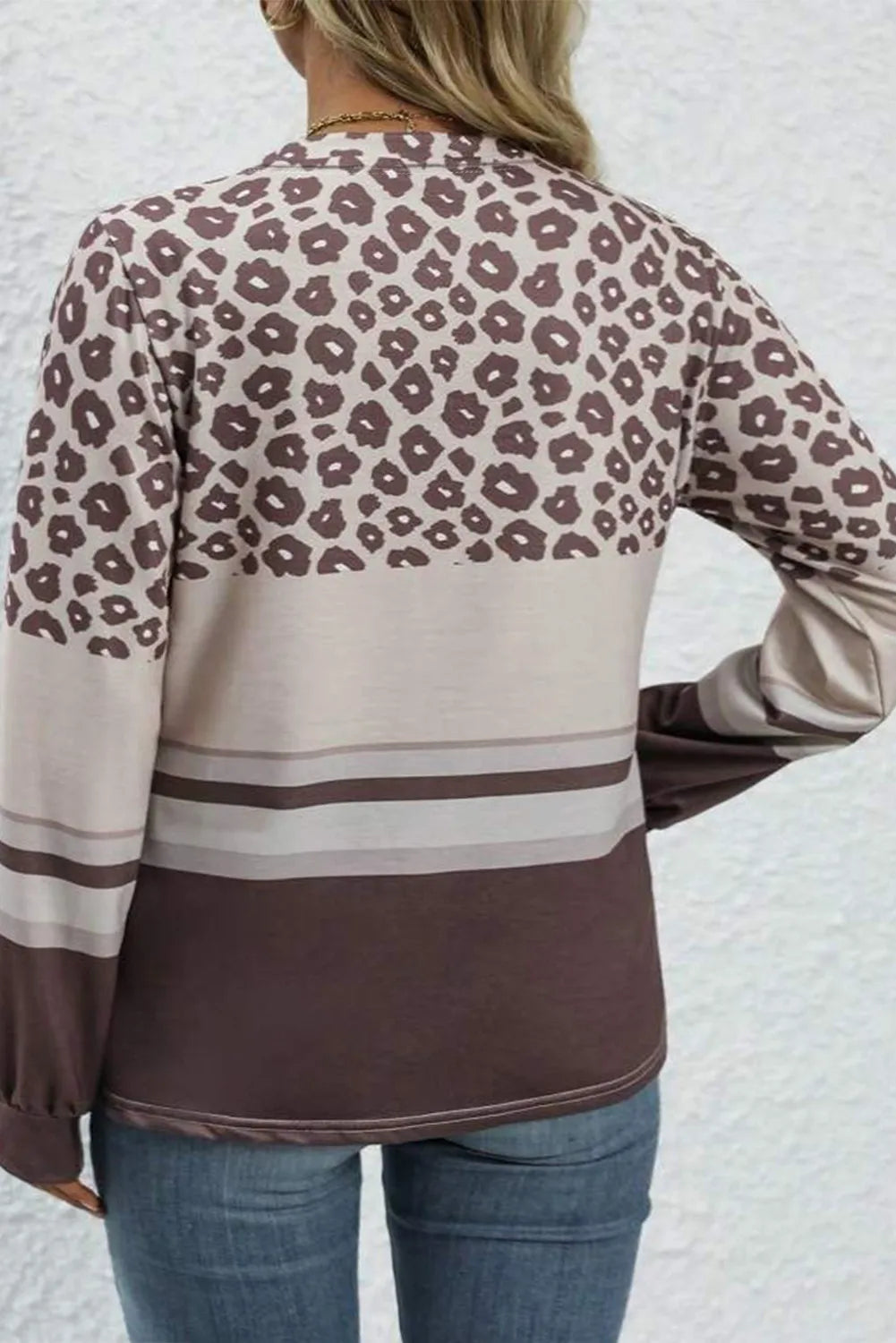 Leopard print crewneck top with horizontal stripes and long sleeves.