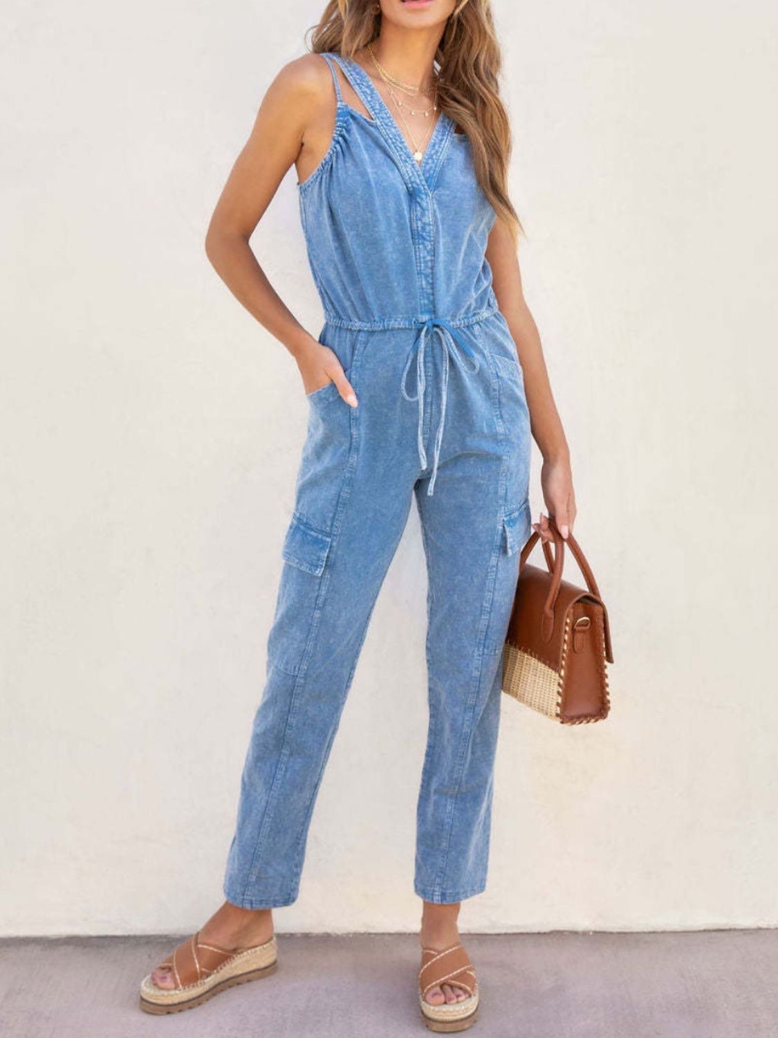 Acid wash cargo jumpsuit with drawstring waist and V-neck in medium blue.