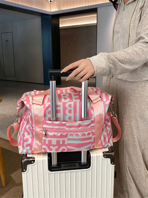 Pink travel bag with white and blue letter print, versatile straps, and front zip pocket.