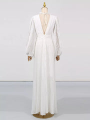White maxi dress with deep V-back, tie neck, and textured balloon sleeves.