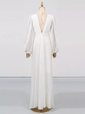 White maxi dress with deep V-back, tie neck, and textured balloon sleeves.