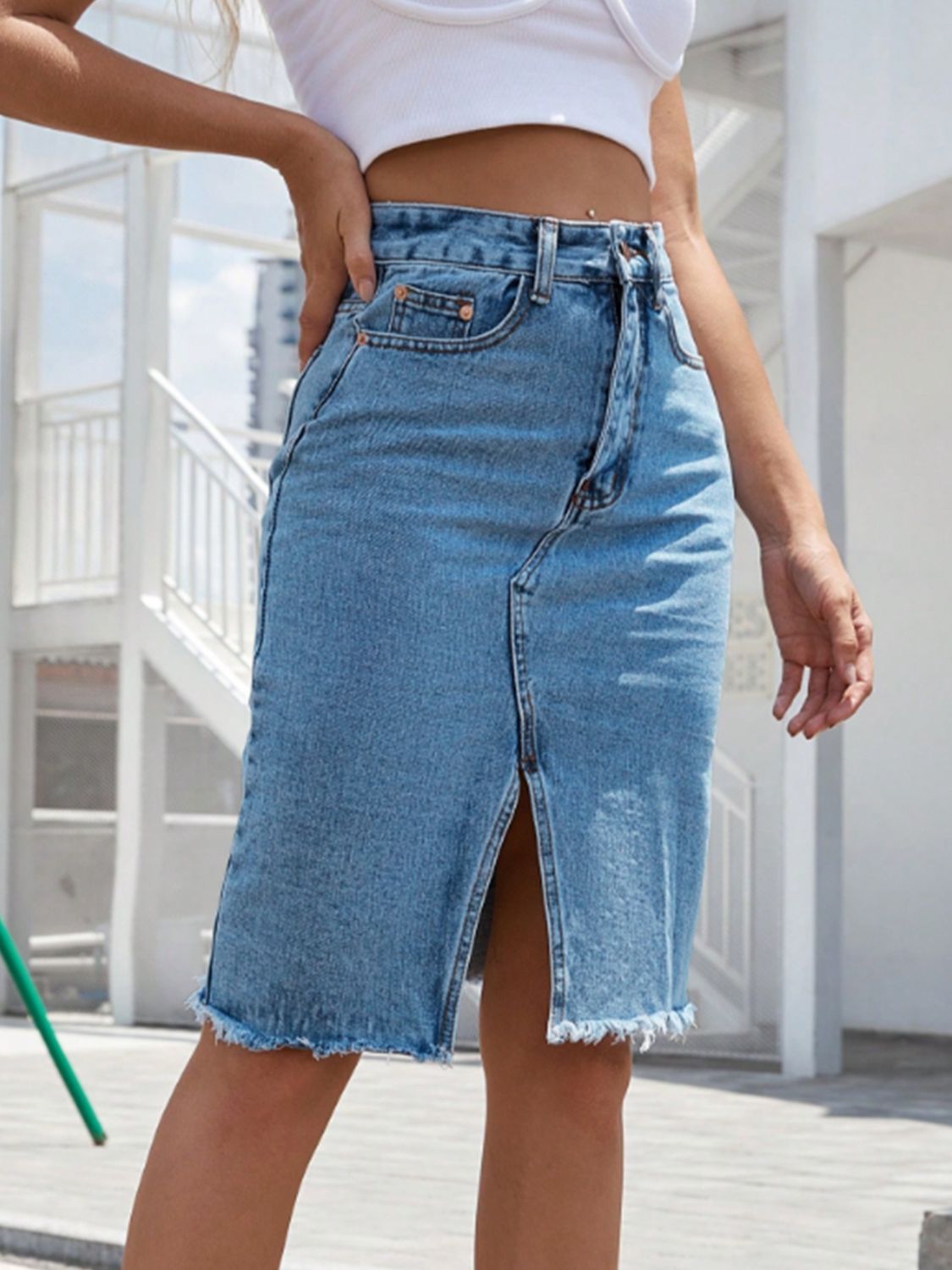 Slit-front frayed denim pencil skirt in light blue with a raw hem.