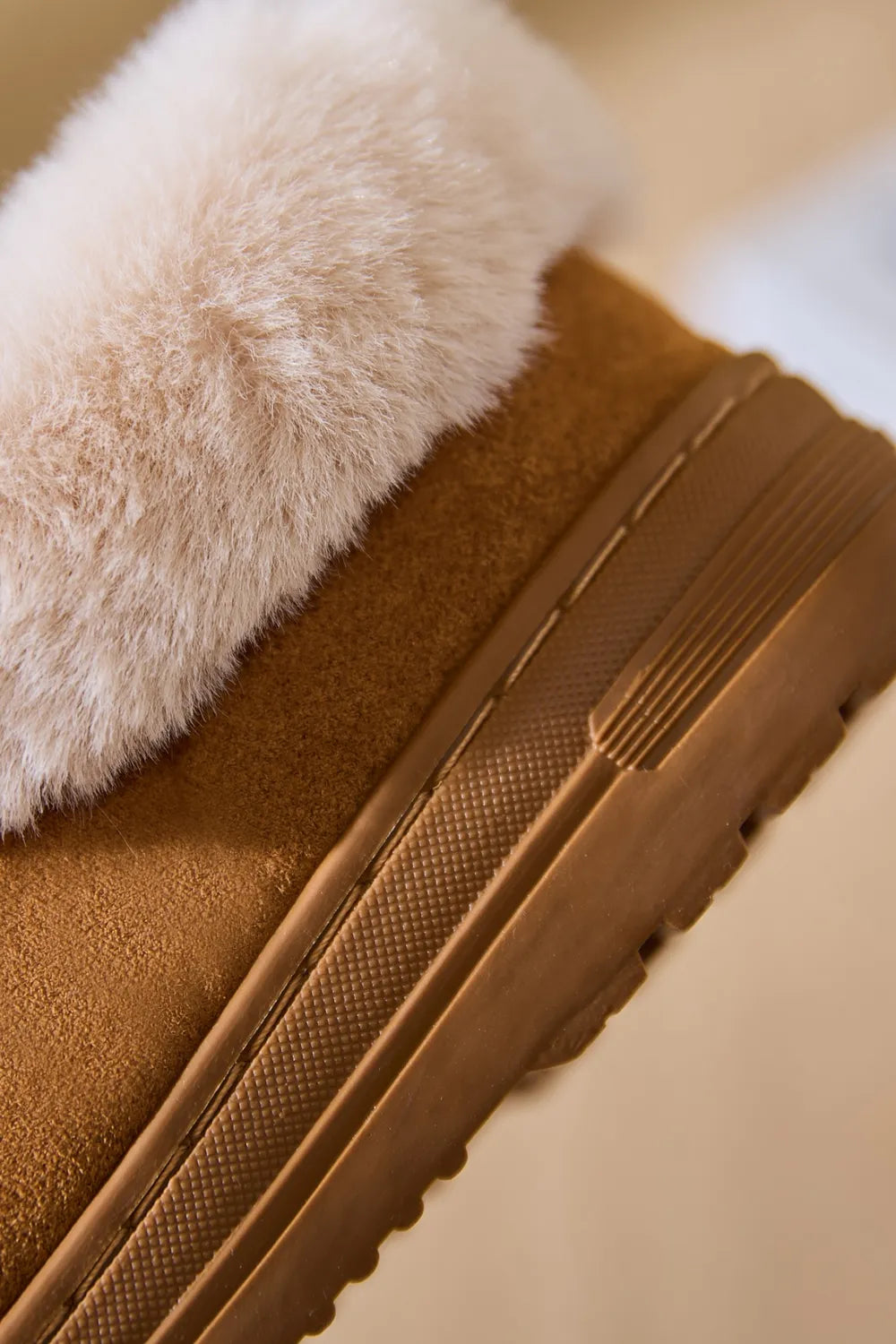 Caramel suede house slippers with plush shearling trim and a textured sole.