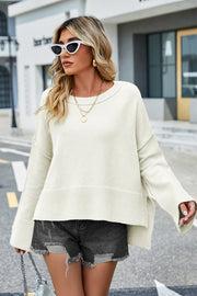 Cream acrylic knit sweater with flared sleeves and slit hem, styled with denim shorts.
