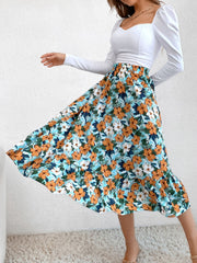 Tiered midi skirt with orange and white floral print on a blue background, ruffled hem
