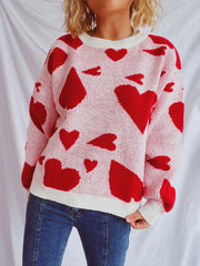 Pink knit sweater with red heart pattern, crew neck, long sleeves, and white trim.