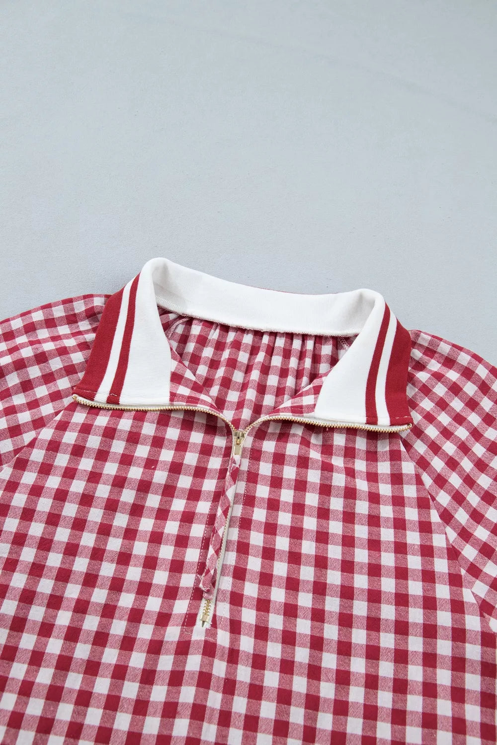 Red gingham cotton blend shirt with half zip and striped collar detail.
