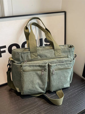 Green corduroy crossbody bag with multiple zippered pockets and top handles.