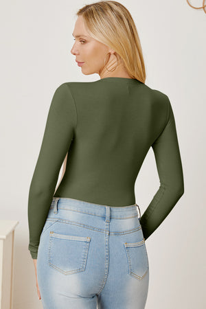 Ribbed long sleeve bodysuit in Matcha Green with a plunge neckline, styled with light wash jeans.
