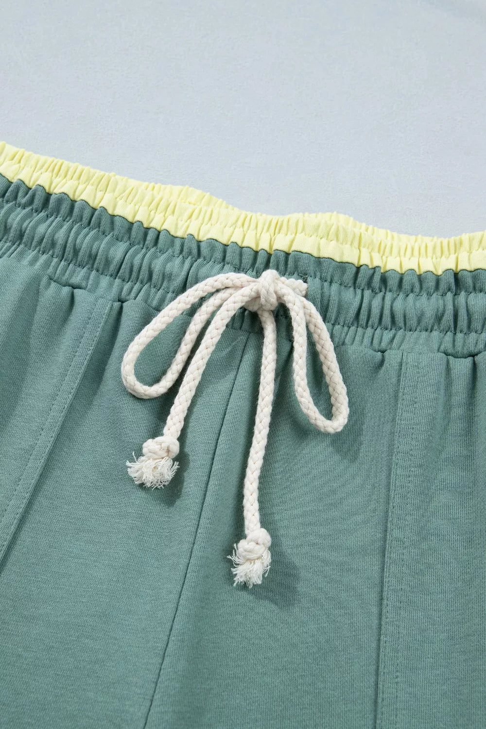Green cotton sweatpants with yellow waistband and white drawstring.