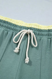 Green cotton sweatpants with yellow waistband and white drawstring.