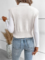 White knit vest with ribbed trim and button detail, worn over a turtleneck.