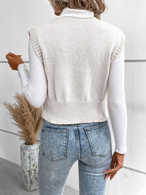 White knit vest with ribbed trim and button detail, worn over a turtleneck.