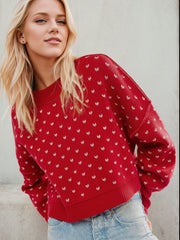 Dotted knit cropped crewneck sweater in Deep Red with a white dot pattern, crew neck, and ribbed cuffs.