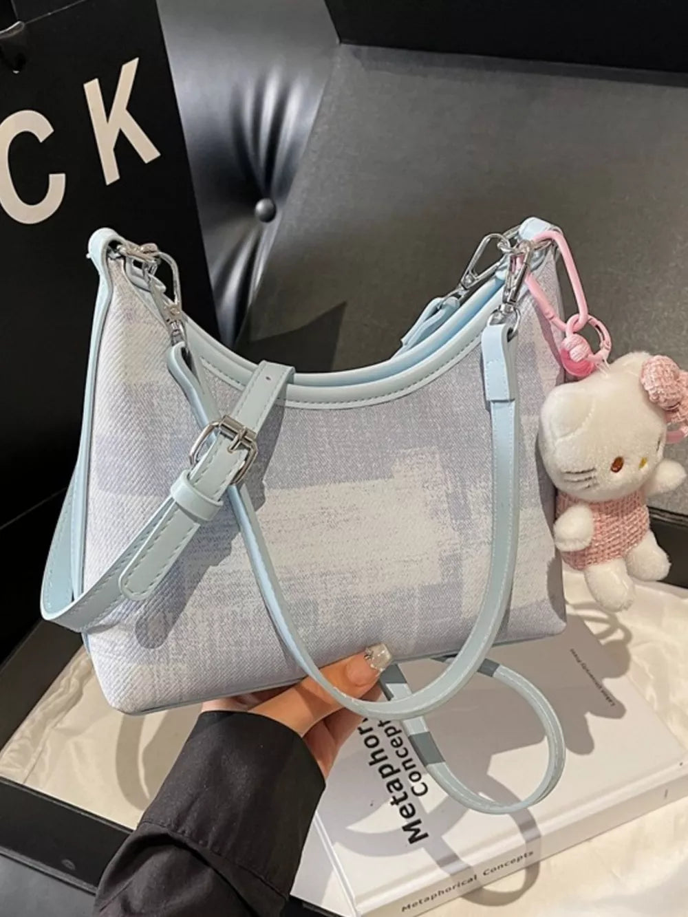 Blue crescent mini shoulder bag with Hello Kitty charm and light blue trim.