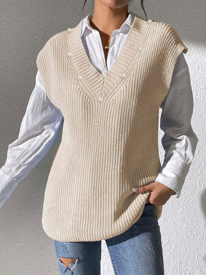Beige ribbed knit sleeveless v-neck vest with pearl embellishments over a white shirt.