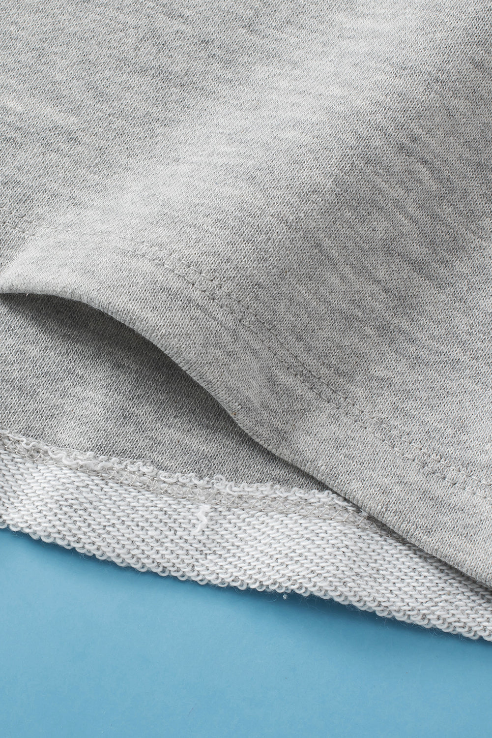Light gray sweatshirt with a pocket detail and ribbed hem.