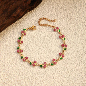 Gold-plated bracelet with pink cherry clusters and green leaves, featuring a delicate chain.