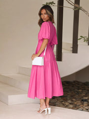 Hot pink midi dress with puff sleeves and tiered skirt.