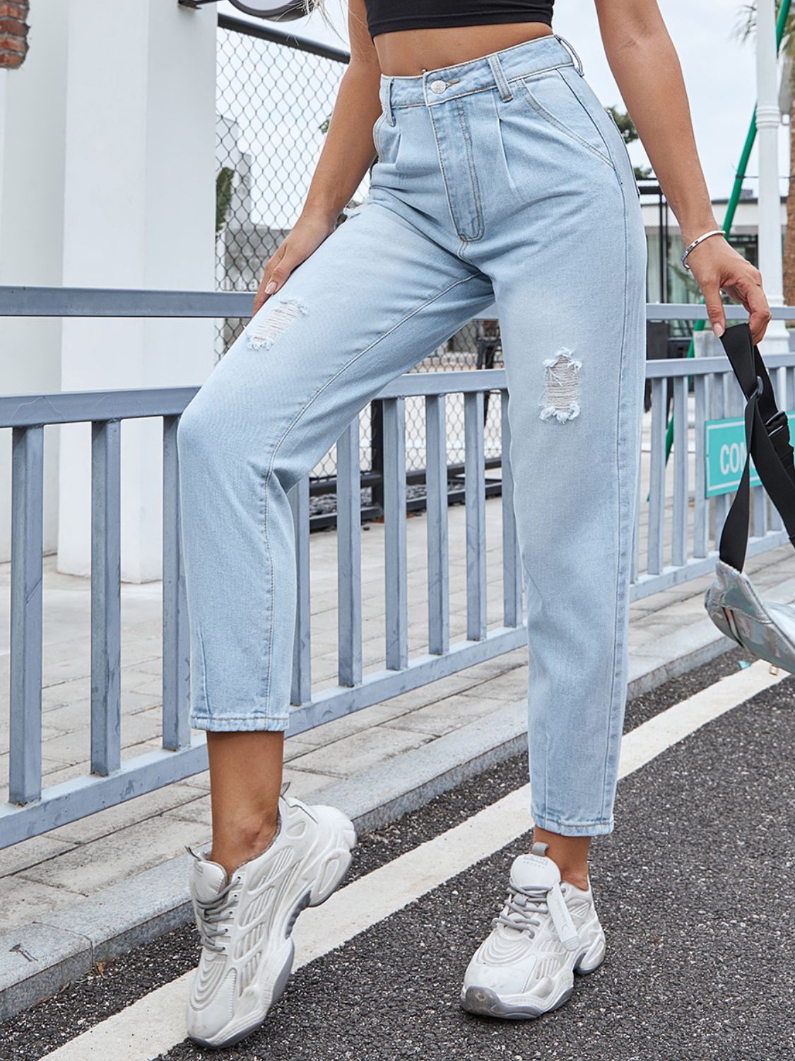 Light wash denim jeans with high rise, pleats, and distressed details.