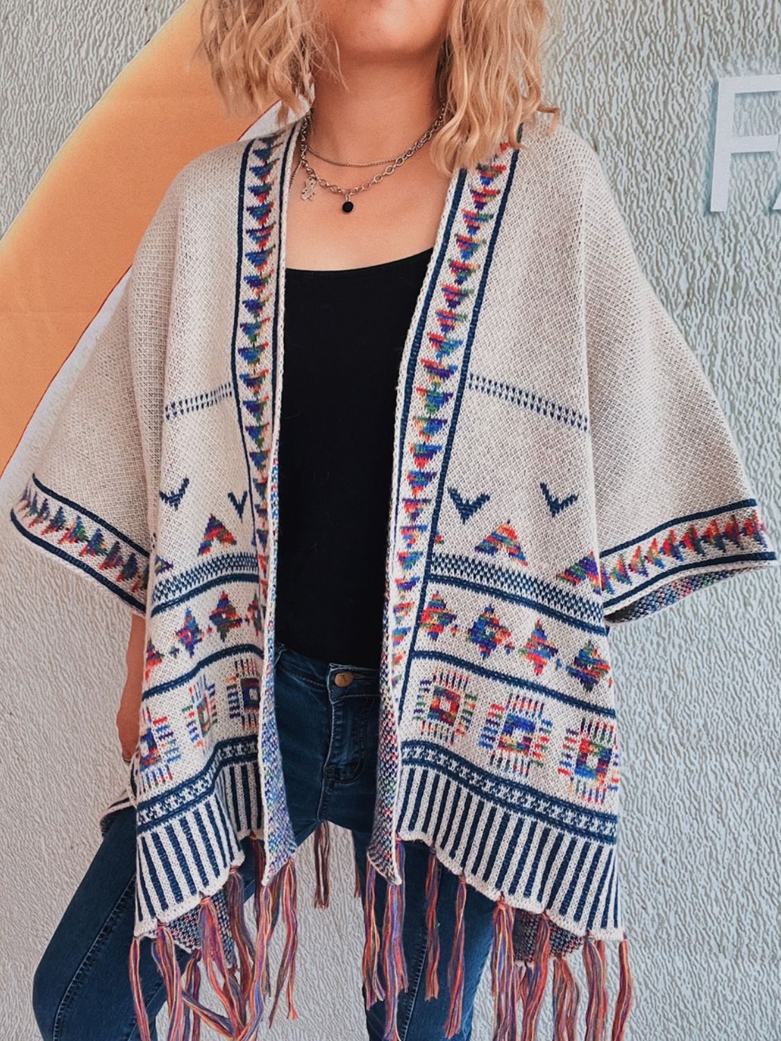 Apricot kimono with embroidered trim and colorful fringe hem, featuring geometric patterns.