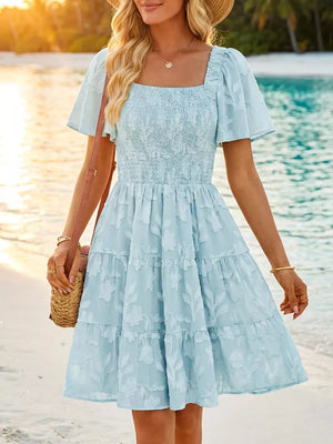 Light blue smocked mini dress with tiered skirt and floral texture, square neck, puff sleeves