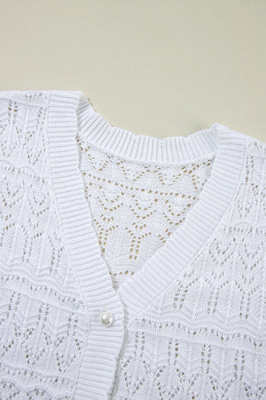 White openwork crochet cardigan with V-neck and pearl button detail.