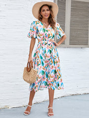 Botanical print midi dress with V-neck, flutter sleeves, tiered skirt, and tie waist.