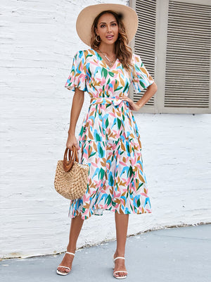 Botanical print midi dress with V-neck, flutter sleeves, tiered skirt, and tie waist.